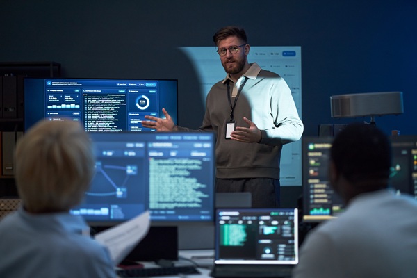 Junger Mann, der dem Team Daten zur Cybersicherheit präsentiert.